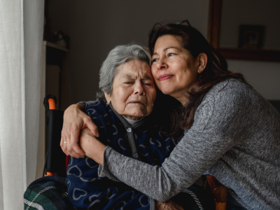 Adult daughter hugging elderly mother in wheelchair 